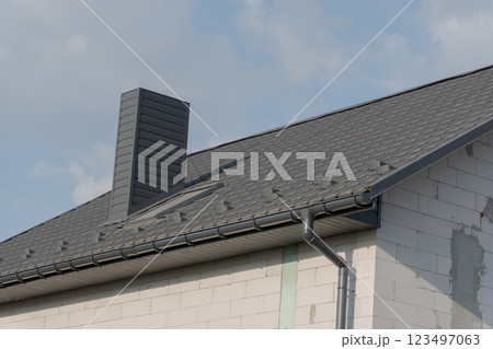 A stylish rooftop highlights contemporary architecture, featuring a prominent chimney and elegant shingles. The bright sky adds a sense of openness and tranquility, enhancing the overall aesthetic A stylish rooftop highlights contemporary architecture, featuring a prominent chimney and elegant shingles. The bright sky adds a sense of openness and tranquility, enhancing the overall aesthetic 123497063