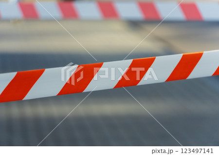 Vibrant orange and white striped barrier tape stretches across the path, signaling a construction zone in a bustling city, urging pedestrians to detour Vibrant orange and white striped barrier tape stretches across the path, signaling a construction zone in a bustling city, urging pedestrians to detour 123497141