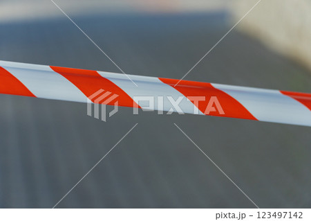 Brightly colored cautionary tape blocks access to a deserted pathway, highlighting a restricted area in an urban environment, illuminated by the midday sun 123497142