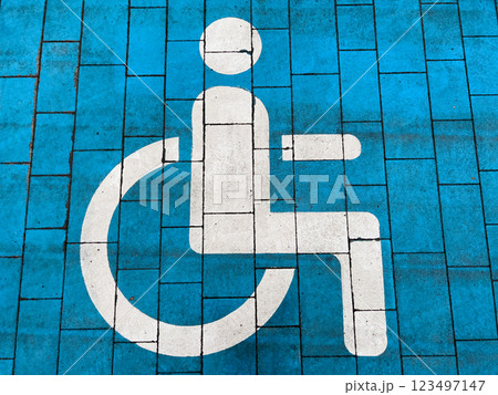 Bright blue pavement displays a clear accessibility symbol, promoting inclusivity in urban environments. This inviting marking encourages awareness and support for individuals with disabilities Bright blue pavement displays a clear accessibility symbol, promoting inclusivity in urban environments. This inviting marking encourages awareness and support for individuals with disabilities 123497147