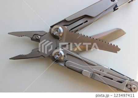Camping Tools and Equipment Stock Image. Universal Multi Tool with Crossed Knife and Saw Blades on White Table Camping Tools and Equipment Stock Image. Universal Multi Tool with Crossed Knife and Saw Blades on White Table 123497411