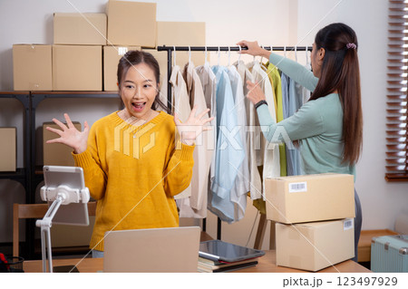 Two young asian woman live online clothing store while showing clothing with tablet and laptop. Two young asian woman live online clothing store while showing clothing with tablet and laptop. 123497929