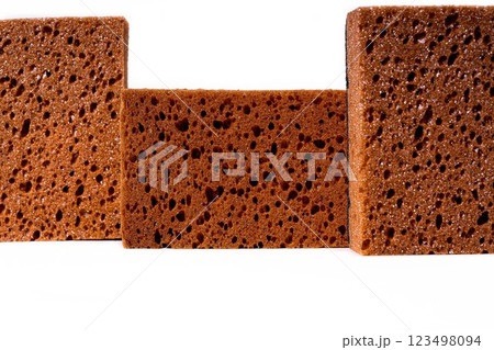 Three textured sponges with a rich brown color, showcasing a porous structure against a clean white background. 123498094