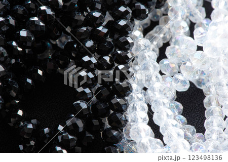 A close-up image showcases a beautiful arrangement of glossy black and crystal-clear beads, highlighting their intricate facets and shine. A close-up image showcases a beautiful arrangement of glossy black and crystal-clear beads, highlighting their intricate facets and shine. 123498136