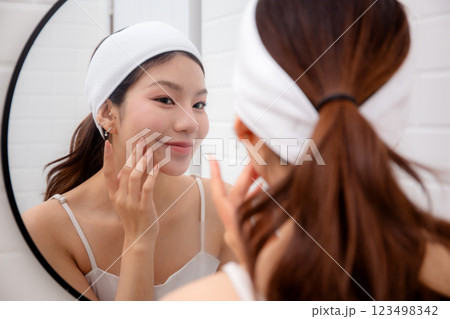 Beautiful young asian woman complexion while looking mirror in bathroom at home. Beautiful young asian woman complexion while looking mirror in bathroom at home. 123498342