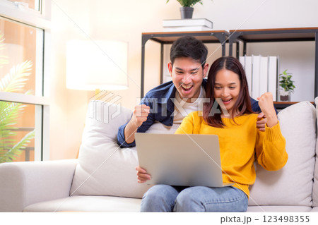 Young asian couple looking on laptop for relax with cozy and success sitting on sofa in living room. Young asian couple looking on laptop for relax with cozy and success sitting on sofa in living room. 123498355