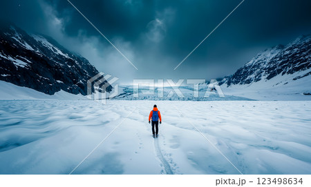 A person walking across a snow covered field with mountains in the background A person walking across a snow covered field with mountains in the background 123498634