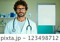 A man in a white lab coat with a stethoscope standing in a hospital room 123498712