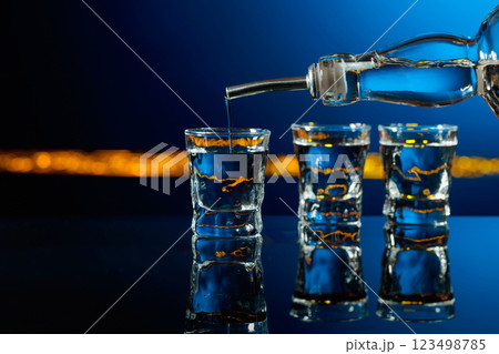 Vodka is poured into a shot glass. 123498785