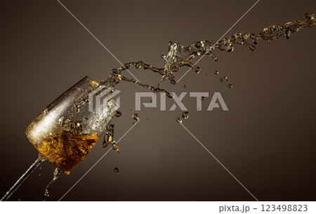 Glass and white wine splash on a beige background. Glass and white wine splash on a beige background. 123498823