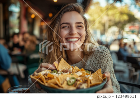 Happy Woman Eating Nachos at Outdoor Cafe 123499611