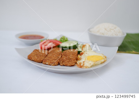 Fried tempeh cutlet with rice and fried egg on white plate 123499745