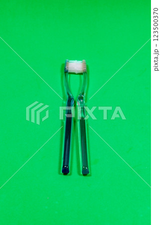 Two toothbrushes facing each other on a green surface Two toothbrushes facing each other on a green surface 123500370