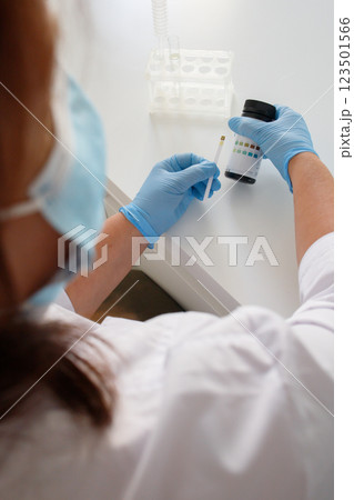 Medical laboratory nurse checking the glucose levels in urine using express strips 123501566