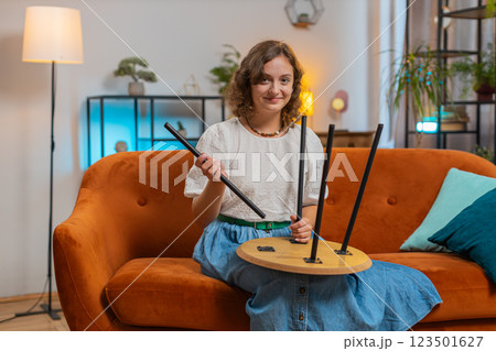 Happy Caucasian young woman finishing assembling furniture after moving into new apartment home Happy Caucasian young woman finishing assembling furniture after moving into new apartment home 123501627