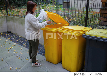 Woman throwing away plastic waste outdoors 123502075