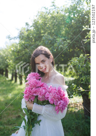 Brunette girl with pink peonies bouquet portrait 123502197