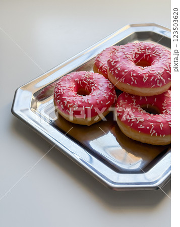 Donuts with pink glaze on metal tray side view 123503620