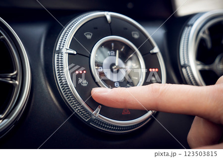 Turning on the heated seats in the car. In close-up, you can see how a finger carefully adjusts the climate control settings on the dashboard of a modern car. Adjusting the cars climate controls 123503815