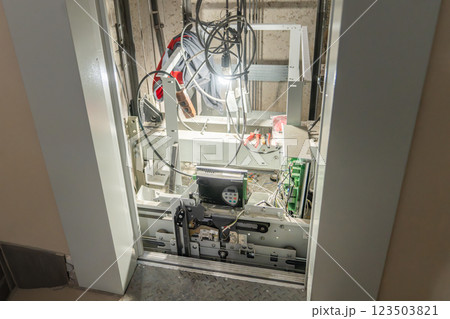 Inspection of Elevator Mechanism featuring Exposed Wiring Components for Safety and Functionality, Elevator doors open during breakage and repair. Elevator maintenance, emergency situation. mine and 123503821