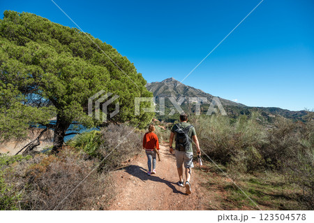 Caucasian male and female hiking in scenic mountain trail under clear blue sky 123504578