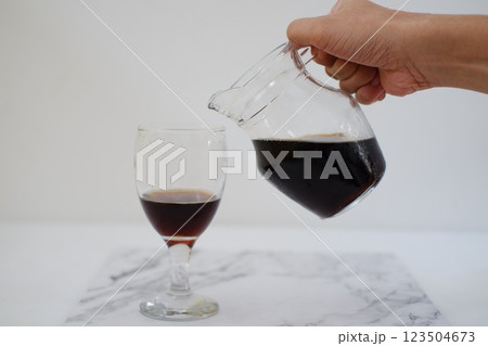 Pouring cola from a jug into a glass on a white background Pouring cola from a jug into a glass on a white background 123504673