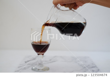 Pouring cola from a jug into a glass on a white background Pouring cola from a jug into a glass on a white background 123504674