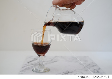 Pouring cola from a jug into a glass on a white background Pouring cola from a jug into a glass on a white background 123504691