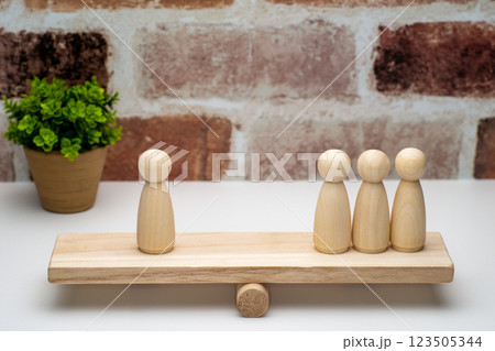 シーソーの上に乗った1対3のペグ人形 123505344