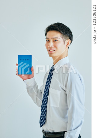 年金手帳を持つ20代の若い男性 123506121