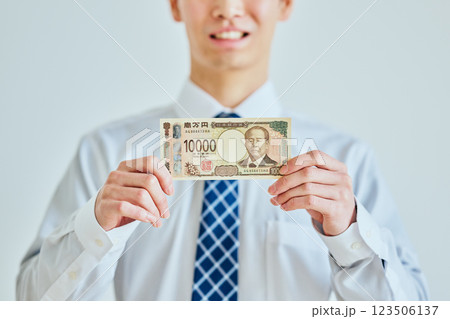 一万円札を持つ20代の若い男性 一万円札を持つ20代の若い男性 123506137