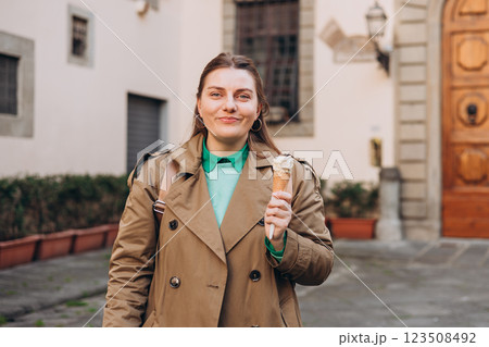 Tasty pistachio ice cream cone in hand. Closeup image of woman hand holding fresh waffle cone with pink ice cream Outdoors, Top Italy food. Lifestyle, travel, people concept. 123508492