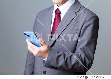 グレーのスーツを着てスマホを持つミドル男性ビジネスマン 123508706