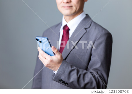 グレーのスーツを着てスマホを持つミドル男性ビジネスマン 123508708
