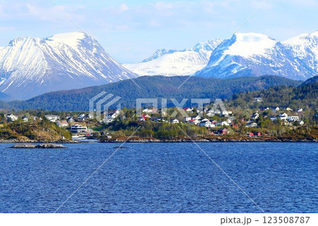 View of the coast of a Norwegian fjord Hardangerfjord with picturesque villages and snow-capped rocky mountains in the background in cruise journey, Norway 123508787