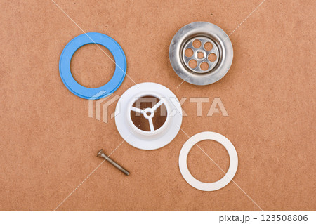 Sink drain assembly components on brown background with metal and plastic parts. Sink drain assembly components on brown background with metal and plastic parts. 123508806