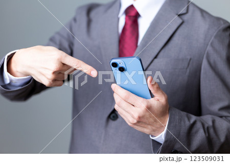 グレーのスーツを着てスマホを指差すミドル男性ビジネスマン グレーのスーツを着てスマホを指差すミドル男性ビジネスマン 123509031