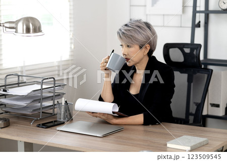 senior businesswoman Sipping coffee while working at a desk using a computer 123509545