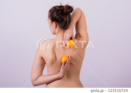 Slender athletic woman topless holds a tangerine in her hands. Cellulite. Healthy lifestyle Slender athletic woman topless holds a tangerine in her hands. Cellulite. Healthy lifestyle 123510729