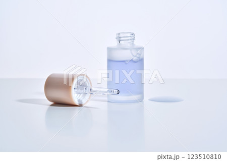 Cosmetic bottle, dropper and a drop of serum on a white background. 123510810