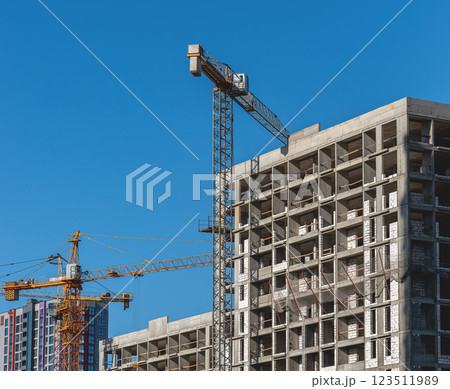 Under construction, modern multi-story condominium in city. Crane working on unfinished facade, part Under construction, modern multi-story condominium in city. Crane working on unfinished facade, part 123511989