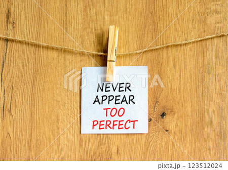 Never appear too perfect symbol. Concept words Never appear too perfect on beautiful white paper on clothespin. Beautiful wooden background. Business never appear too perfect concept. Copy space. 123512024