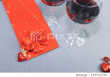 Two glasses with red wine and gift with a heart and an angel on the table. 123512747