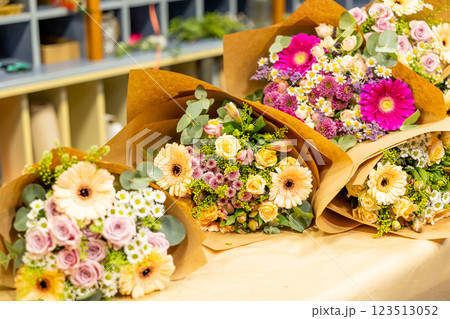 Colorful flower bouquets wrapped in brown paper resting on table Colorful flower bouquets wrapped in brown paper resting on table 123513052