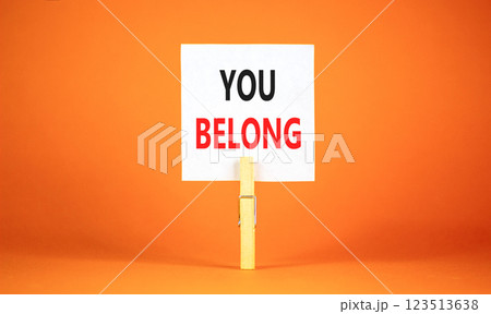 Belonging and you belong symbol. Concept words You belong on beautiful white paper on wooden clothespin. Beautiful orange background. Business belonging and you belong concept. Copy space. 123513638
