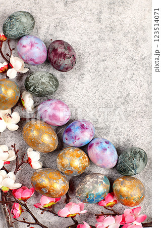 Marble Easter eggs, dyed with golden turmeric and hibiscus tea on a gray concrete background with sakura branches, ideas for homemade Easter cooking, Easter celebration concept 123514071
