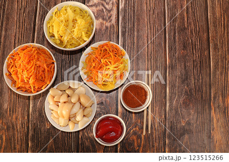 Korean side dishes for a barbecue dinner - kimchi and various kinds of vegetables, a set of fermented foods useful for intestinal health - top view of glass bowls on a wooden background, flat lay, 123515266