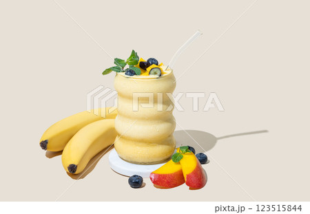 Smoothie with mango, banana and blueberry  in a glass on a yellow background with fruits and shadow. 123515844