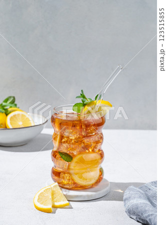Iced tea with lemon, ice and mint in a glass on light texture background with citrus fruits  123515855