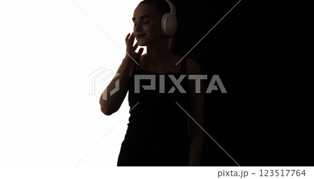DJ silhouette. Music entertainment. Dark contrast outline of peaceful woman headphones enjoying listening audio isolated on white black empty space background. 123517764